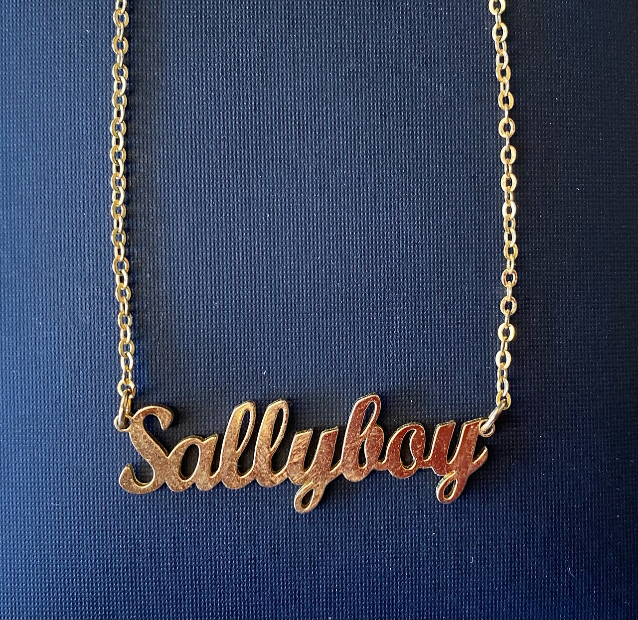before: gold name necklace and fine chains photographed against dark blue fabric