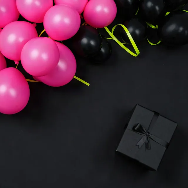 Hot-pink and black balloons with yellow-green ribbon on black paper, empty center