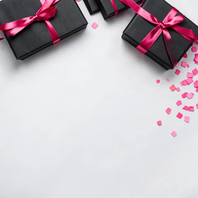 Black gift boxes with hot-pink ribbon and pink confetti on pale gray paper