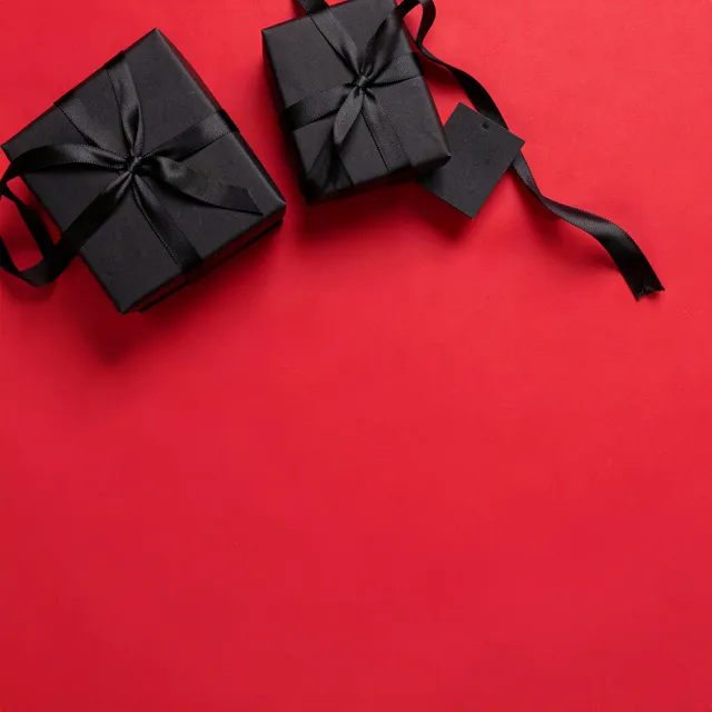 Black gift boxes with black satin ribbon along the top edge of red paper