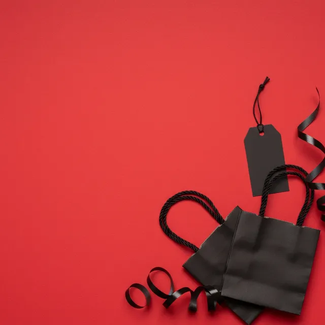 Black Friday sale background: black shopping bags and a blank tag on red paper