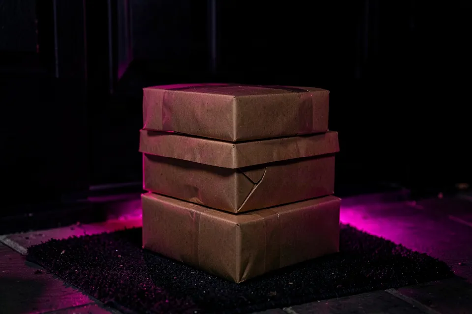 Black Friday parcels on a doormat lit by pink light at night