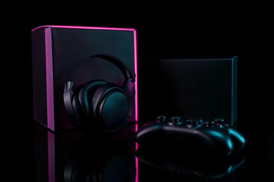 Gaming headset and controller lit pink and cyan on a glossy black surface