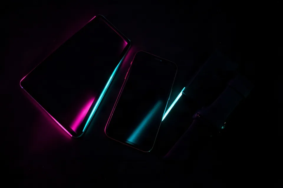 Tablet, phone and smartwatch crossed by pink and cyan light bands