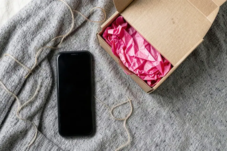 Soft gray blanket with an opened kraft parcel, pink tissue paper and loose twine