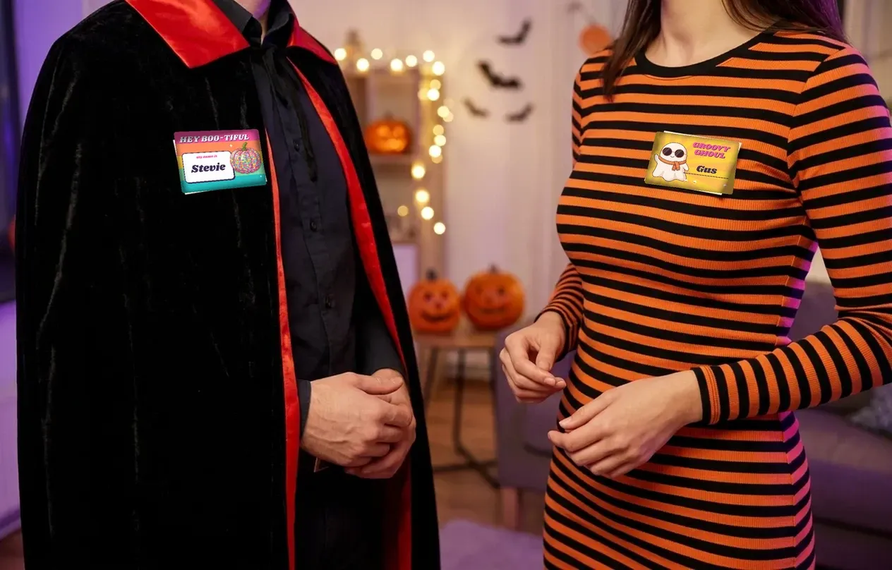 Party guests in a vampire cape and striped dress wearing Hey boo-tiful and Groovy ghoul badges