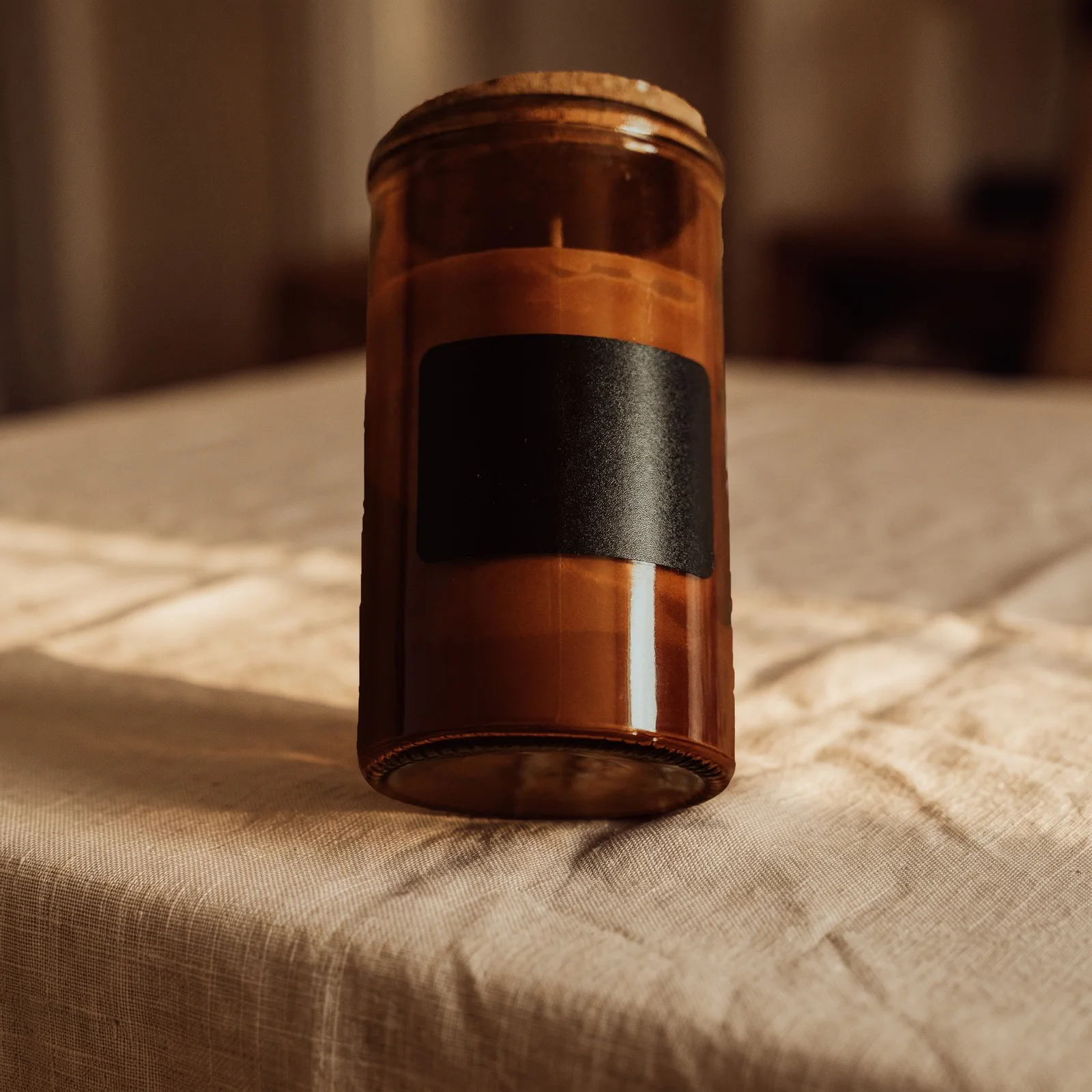 unbranded amber glass candle on softly lit linen