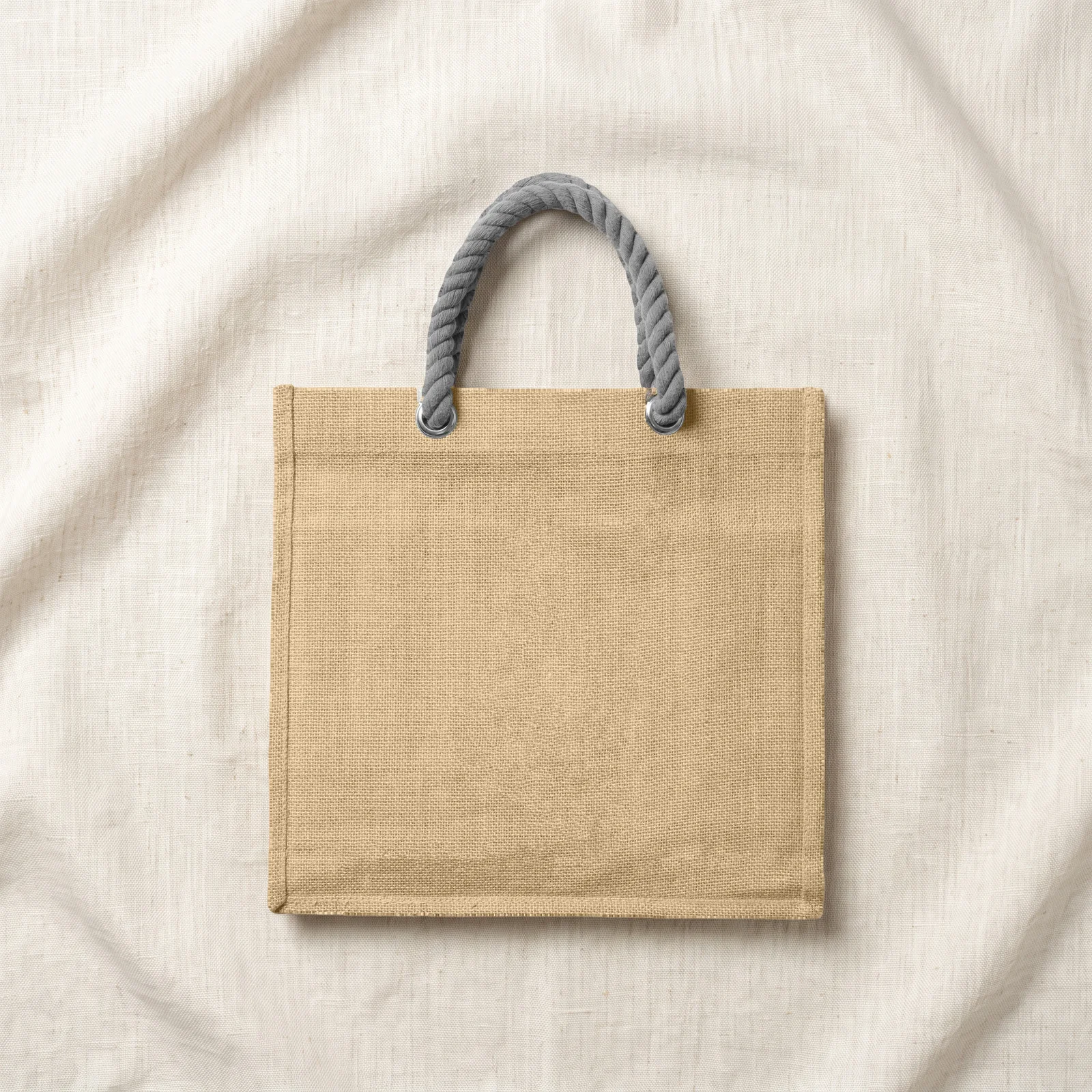 The same jute tote on cream fabric with folds and soft shadows