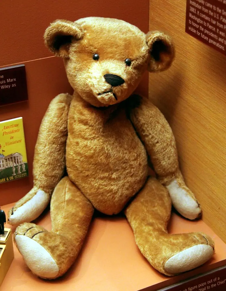 before: plush bear with pale paws photographed beside boxes on a seat