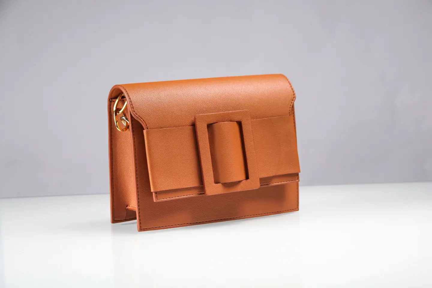 tan leather handbag product photo on a pale backdrop