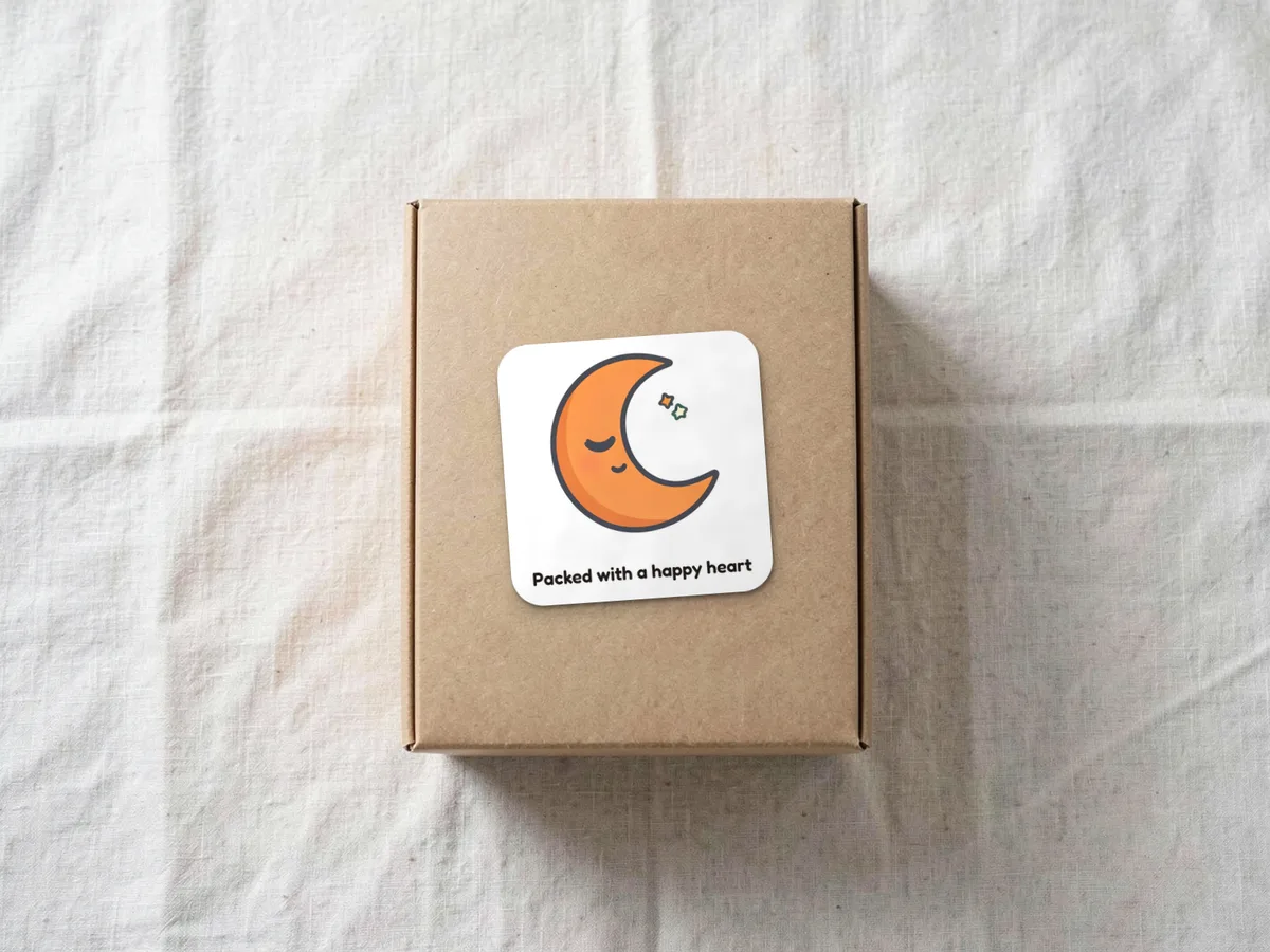 Sleeping moon sticker reading Packed with a happy heart on a kraft mailer box